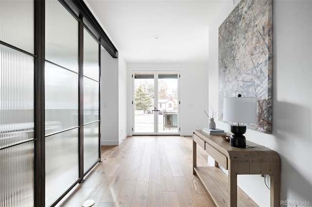 hallway with french doors, light wood-type flooring, and baseboards