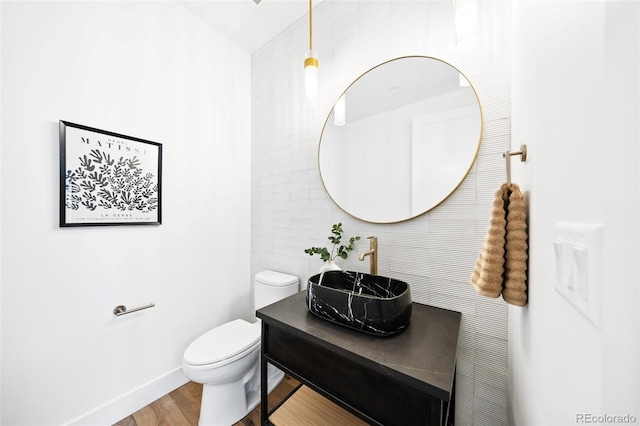 bathroom with vanity, toilet, wood finished floors, and baseboards