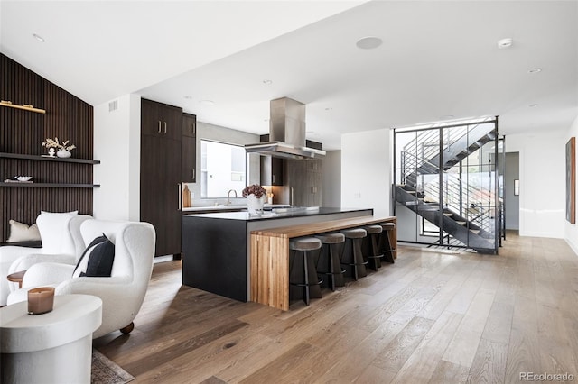 kitchen featuring visible vents, a kitchen bar, island exhaust hood, light wood-style floors, and modern cabinets