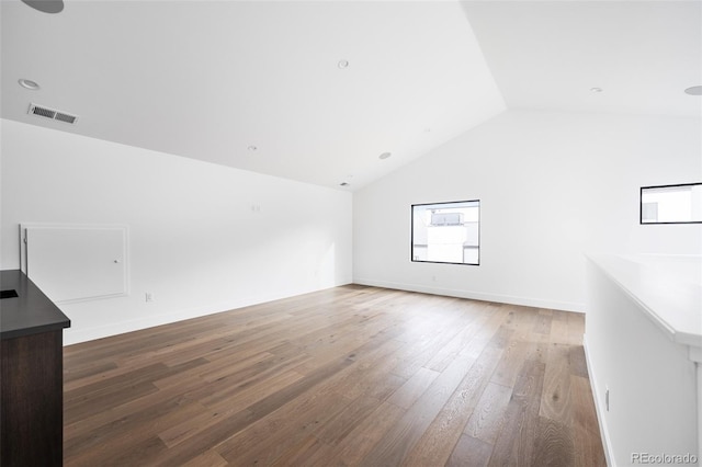 spare room with visible vents, lofted ceiling, baseboards, and wood finished floors