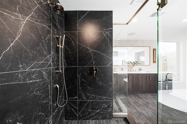 bathroom with a marble finish shower, visible vents, a sink, and double vanity