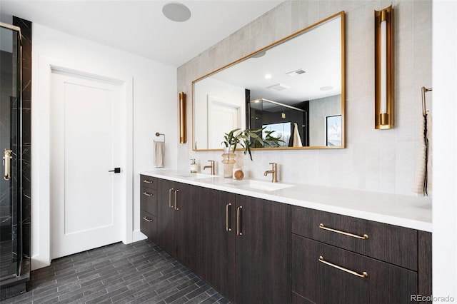 full bath featuring double vanity, visible vents, a stall shower, and a sink