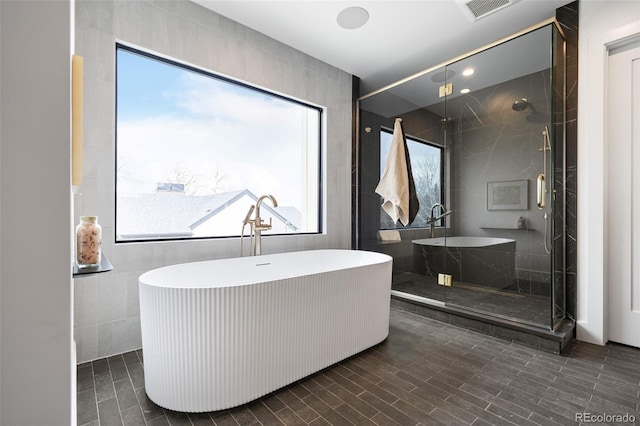 bathroom with visible vents, a soaking tub, tile walls, and a shower stall