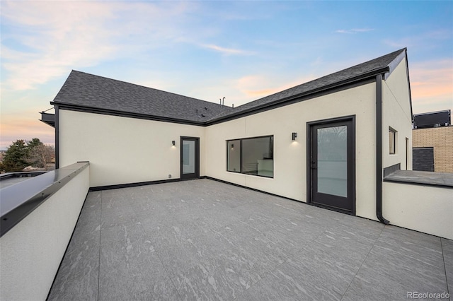 back of property with stucco siding, a shingled roof, and a balcony