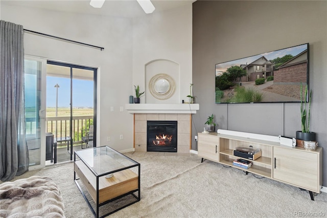 23376 E 5th Pl Unit 201, Aurora, CO 80018 - living area with carpet, a ceiling fan, a tiled fireplace, and a towering ceiling
