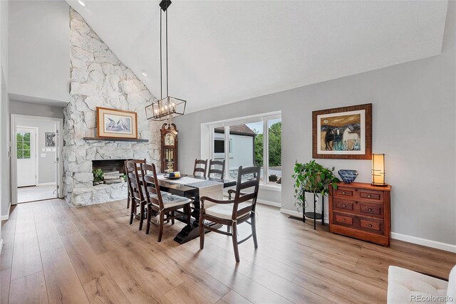 9053 Clydesdale Rd, Castle Rock, CO 80108 - dining room with baseboards, a fireplace, healthy amount of natural light, light wood-style floors, and high vaulted ceiling