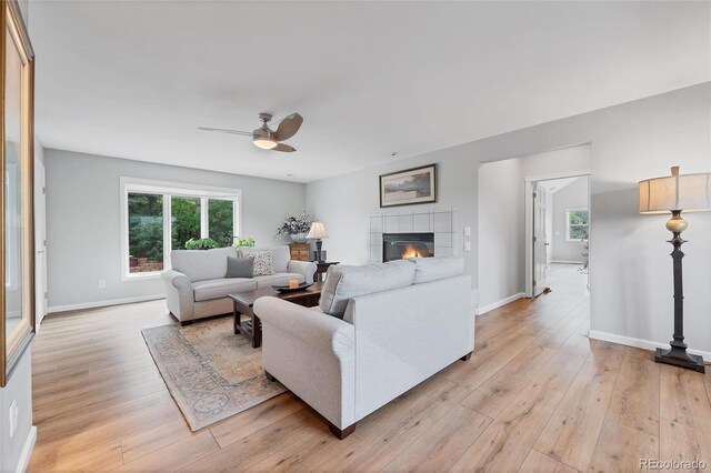 9053 Clydesdale Rd, Castle Rock, CO 80108 - living room featuring ceiling fan, light wood-style floors, a tiled fireplace, and baseboards