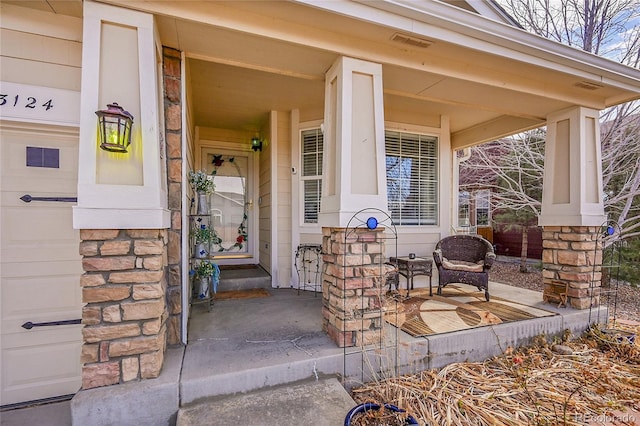 entrance to property featuring covered porch, stone siding, visible vents, and a garage