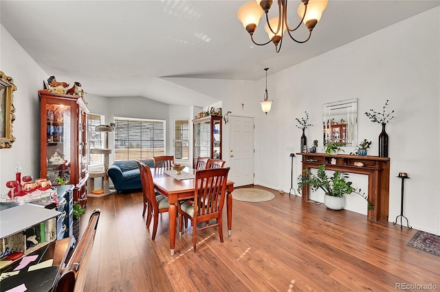 dining room featuring lofted ceiling, a notable chandelier, and wood finished floors