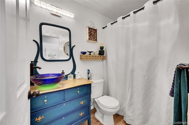 full bath featuring toilet, curtained shower, wood finished floors, and vanity