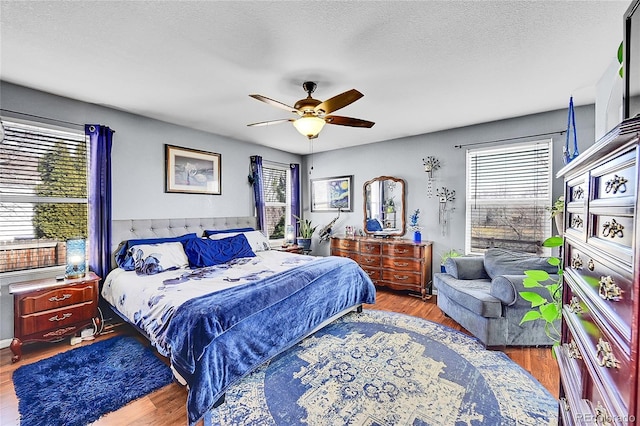 bedroom with multiple windows, a textured ceiling, and wood finished floors