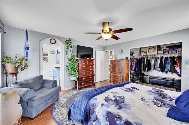 bedroom featuring a closet, visible vents, a ceiling fan, connected bathroom, and wood finished floors