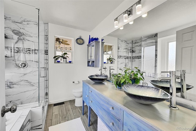 full bathroom with wood tiled floor, toilet, a sink, and a marble finish shower