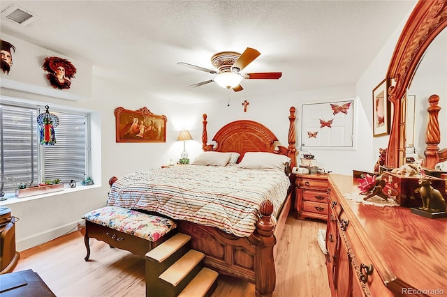 bedroom with visible vents, light wood-style floors, a ceiling fan, a textured ceiling, and baseboards