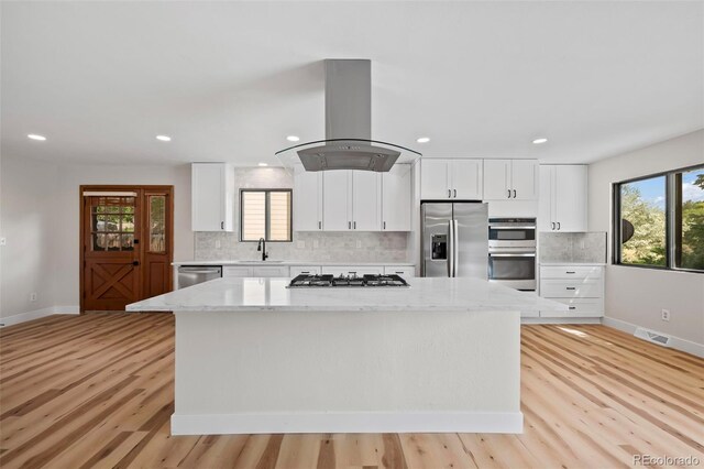 kitchen featuring white cabinets, appliances with stainless steel finishes, a center island, and island exhaust hood