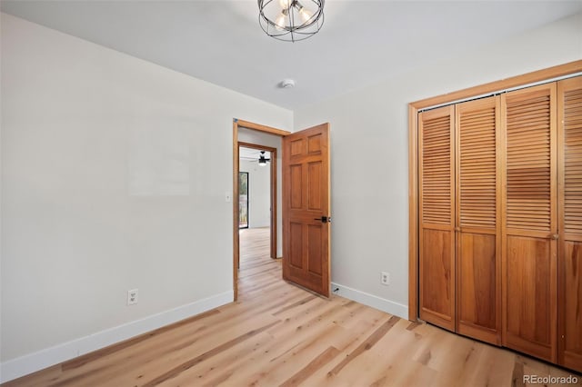 unfurnished bedroom with light wood-style flooring, baseboards, and a closet