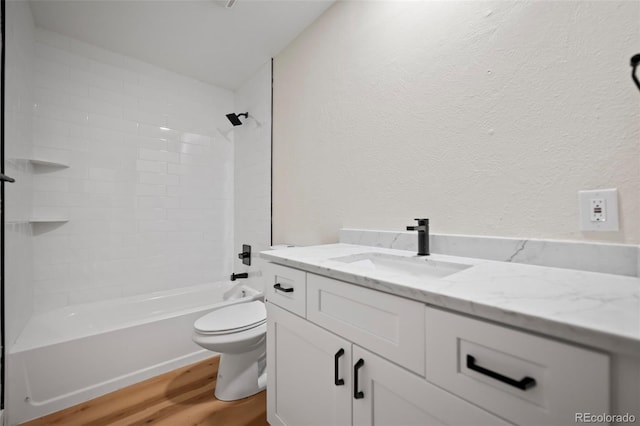 bathroom featuring a textured wall, toilet, vanity, wood finished floors, and shower / bathtub combination