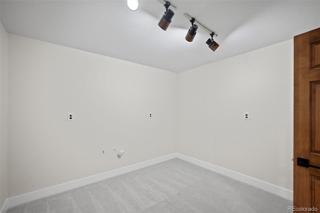 unfurnished room featuring baseboards, track lighting, and light colored carpet