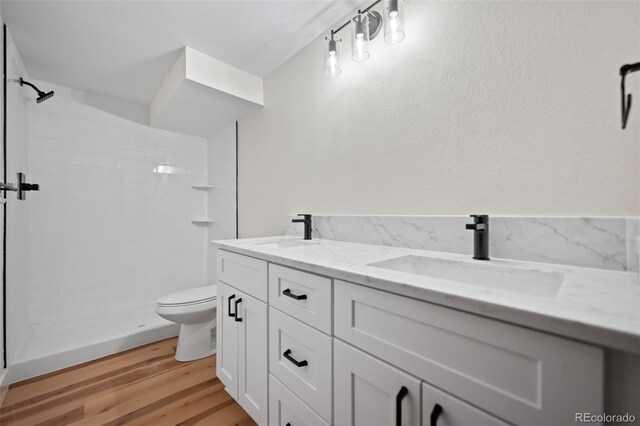 bathroom with vanity, toilet, hardwood / wood-style flooring, and a tile shower