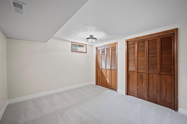 unfurnished bedroom featuring carpet and two closets