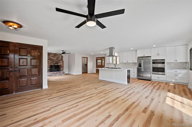 kitchen featuring open floor plan, stainless steel appliances, island exhaust hood, and white cabinetry