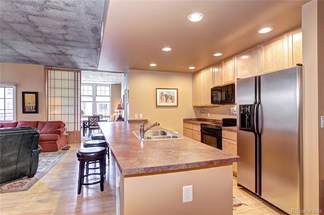 kitchen featuring black appliances, light hardwood / wood-style floors, sink, and plenty of natural light