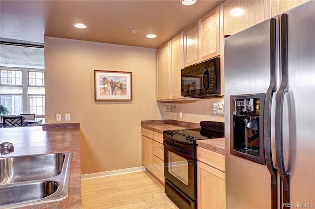 kitchen with light wood-type flooring, black appliances, light brown cabinets, and sink