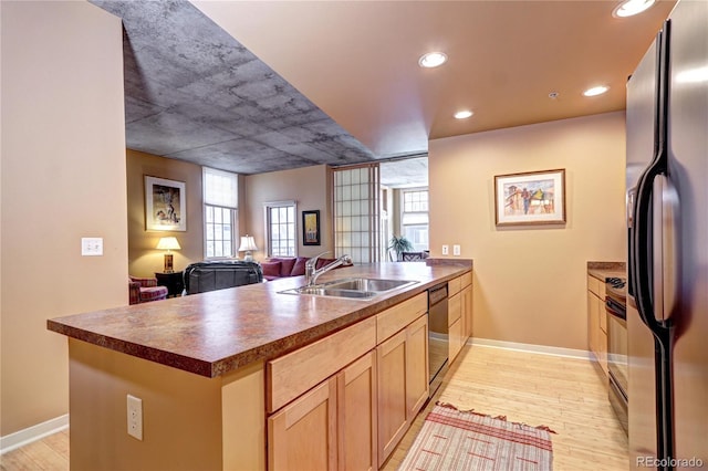 kitchen featuring light brown cabinetry, stainless steel appliances, light wood-type flooring, and sink