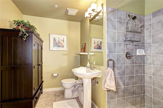 bathroom featuring tile patterned flooring, toilet, and tiled shower