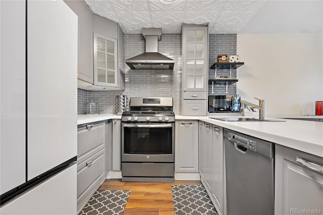 kitchen with black dishwasher, sink, white fridge, stainless steel gas range oven, and wall chimney exhaust hood