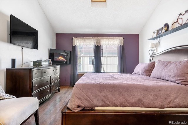 bedroom featuring hardwood / wood-style flooring, vaulted ceiling, and a textured ceiling