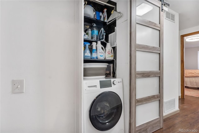 laundry room with a barn door, washer / clothes dryer, and dark wood-type flooring