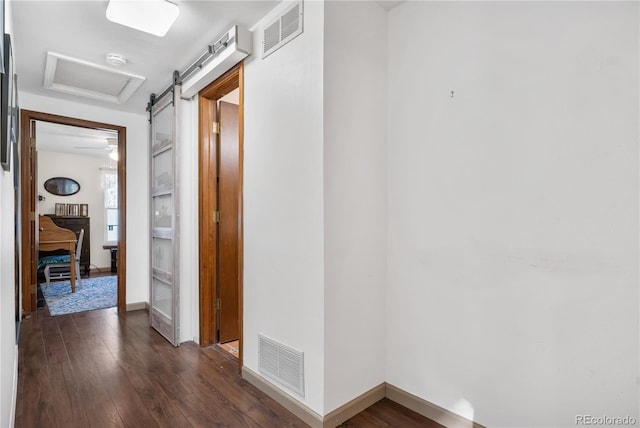 hallway featuring a barn door and dark wood-type flooring