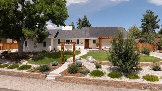 single story home with solar panels, a front yard, and fence