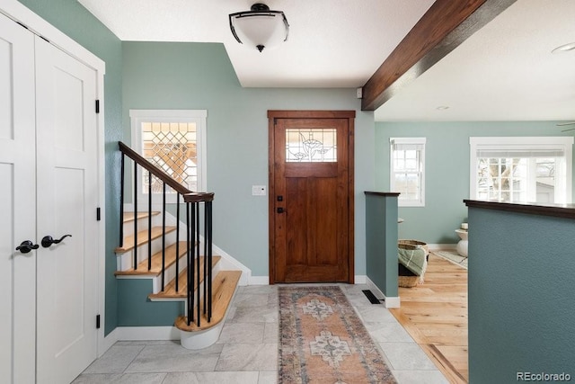 tiled foyer with stairway, baseboards, and beamed ceiling