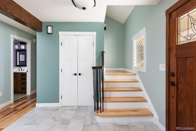 entrance foyer featuring baseboards, lofted ceiling, and stairs