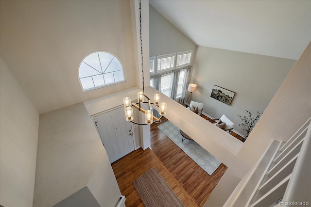 entrance foyer with high vaulted ceiling, wood finished floors, and a chandelier