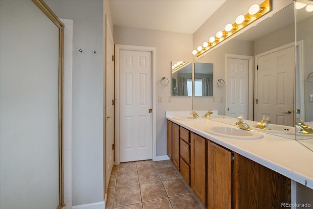 bathroom featuring tile patterned flooring, double vanity, baseboards, and a shower with door