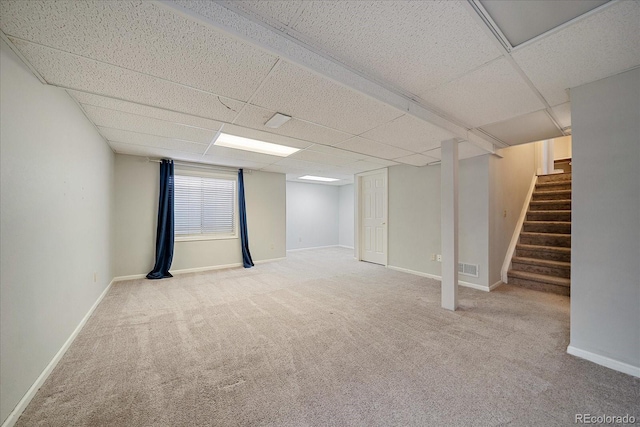 below grade area with a paneled ceiling, carpet, stairs, and baseboards