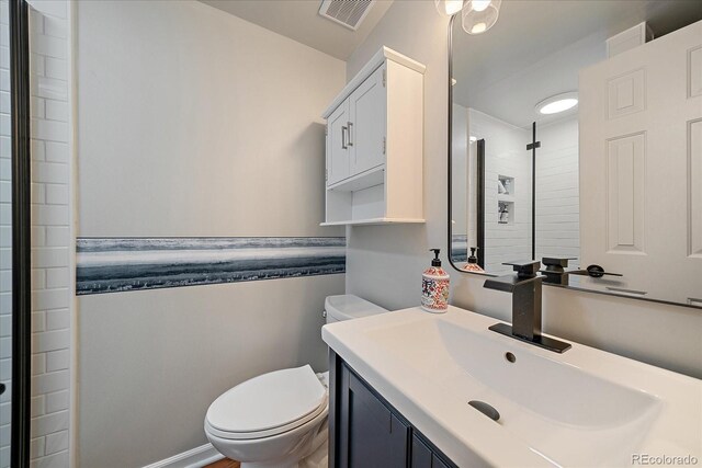 bathroom featuring toilet, vanity, and tiled shower