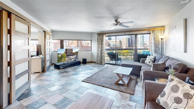 living room with ceiling fan and a textured ceiling