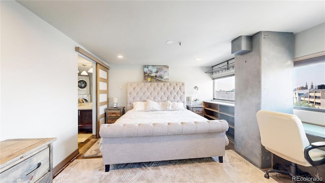 bedroom featuring stacked washer and clothes dryer, light wood-type flooring, and connected bathroom