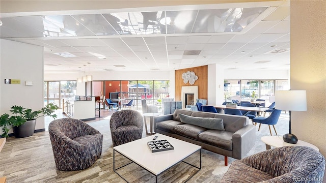 living room with a drop ceiling, light wood-type flooring, and a healthy amount of sunlight