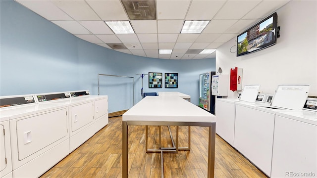 clothes washing area with washing machine and dryer and light hardwood / wood-style flooring