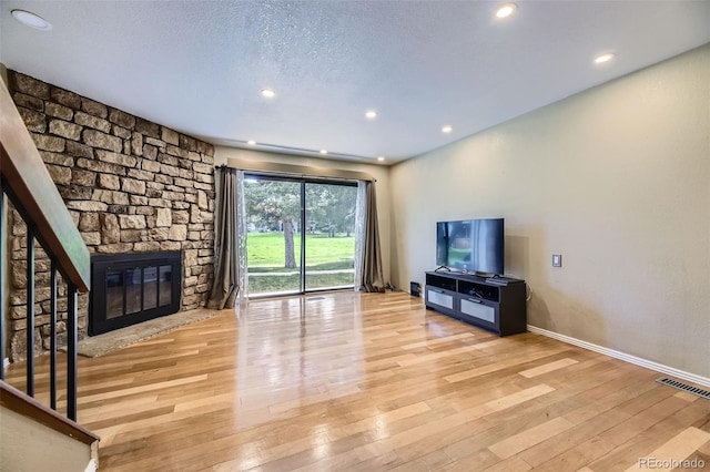 unfurnished living room featuring light wood-style flooring, visible vents, baseboards, a stone fireplace, and recessed lighting