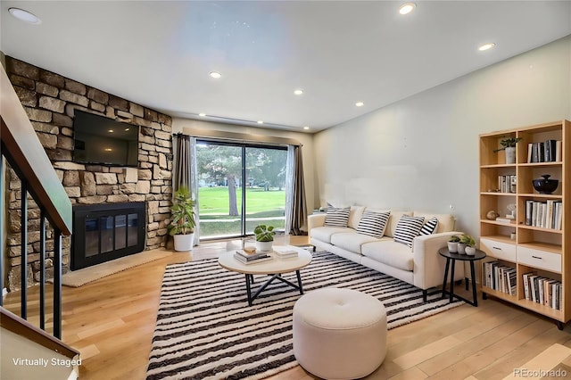 living area with a stone fireplace, recessed lighting, and wood finished floors