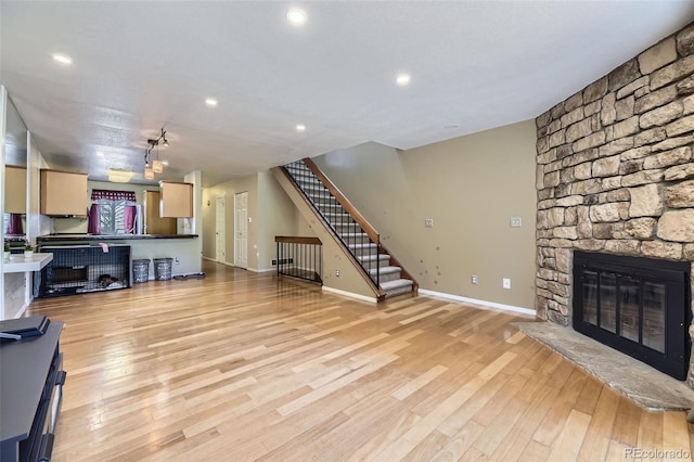 unfurnished living room with stairs, recessed lighting, light wood finished floors, baseboards, and a stone fireplace