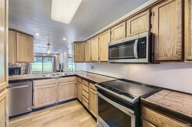 kitchen with light wood-style flooring, recessed lighting, a textured ceiling, a sink, and appliances with stainless steel finishes