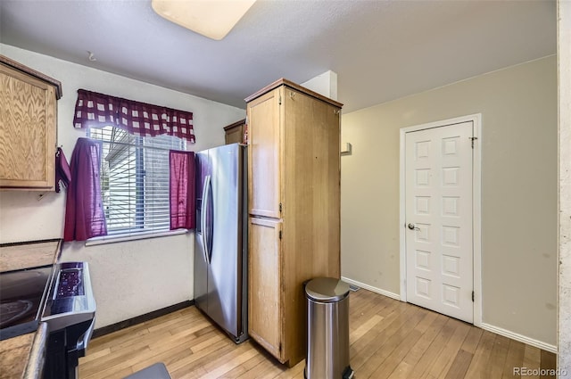 kitchen with light wood finished floors, stainless steel fridge, and baseboards
