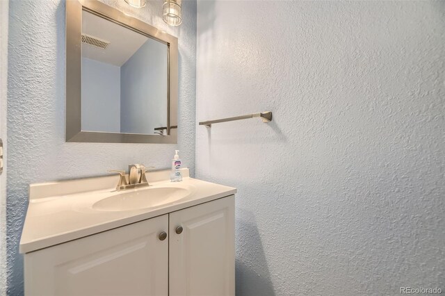 bathroom featuring vanity, a textured wall, and visible vents